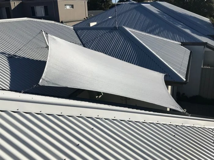 Tensioned shade sail over a paved courtyard